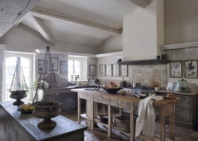 Drewniana wyspa i litografie z ziołami na ścianie w kuchni