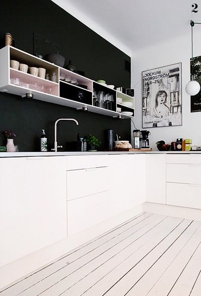 Czarna ściana,grafiki  i białe deski na podłodze w skandynawskiej kuchni