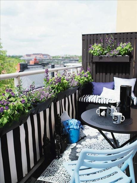 Czarna balustrada na balkonie z wiszącymi fioletowymi kwiatami,aranzacja balkonu w turkusowo-czarnych kolorach,czarny okragły stolik na balkon,czarne meble z metalu na małym balkonie,aranzacja małego balkonu,siedziska z poduchami na małym balkon
