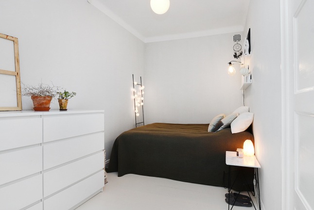 Biała sypialnia bez okien z ciemnobrązową kapą na łóżku