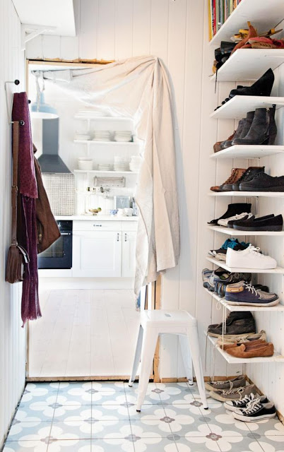 Otwarte półki na buty i dekoracyjna biala zasłona na drzwiach w korytarzu