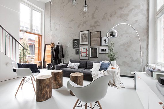 Ściana z betonu dekoracyjnego,biała żywiczna posadzka w salonie,pieńki w roli stolików