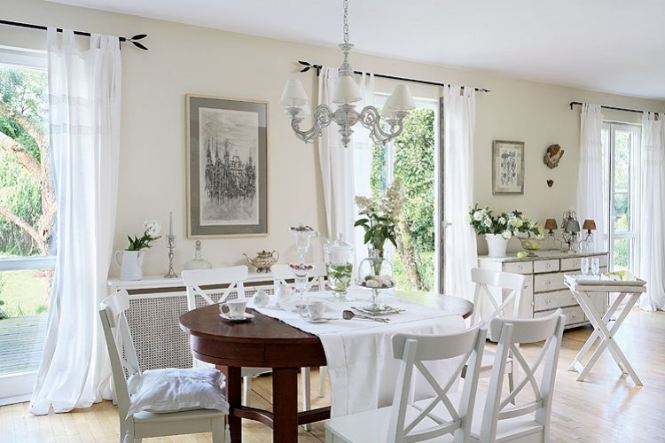 Biala jadalnia z owalnym, brązowym stołem i białymi krzeslami w stylu prowansalskim