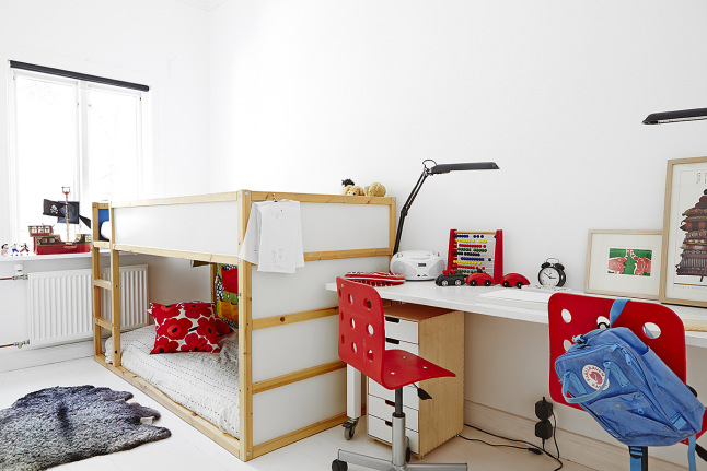 Piętrowe łóżka i podwójne biurkow z czerwonymi krzesłami w dziecięcym pokoju