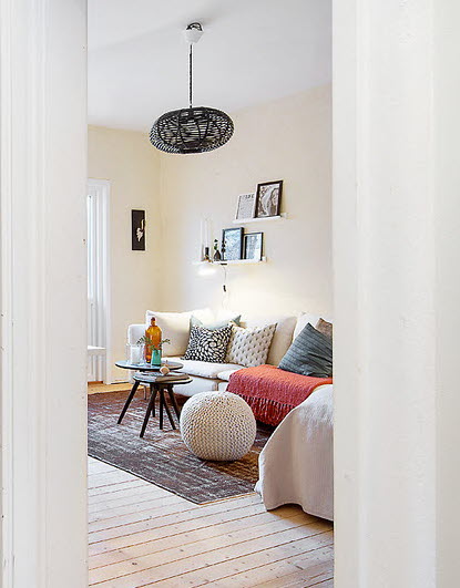 Ażurowa czarna lampa,biala sofa,poduszki dekoracyjne w salonie skandynawskim