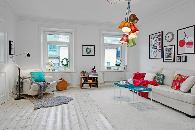 Aranżacja skandynawskiegobiałego salonu z kolorowymi poduszkami i lampą