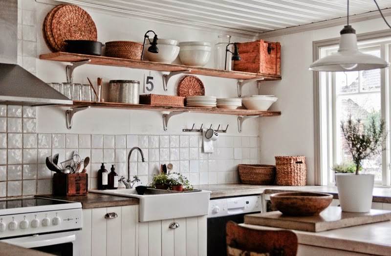 Biała kuchnia rustykalna z drewnianymi półkami na ścianie,miedzianymi naczyniami,wiklinowymi i drewnianymi dekoracjami