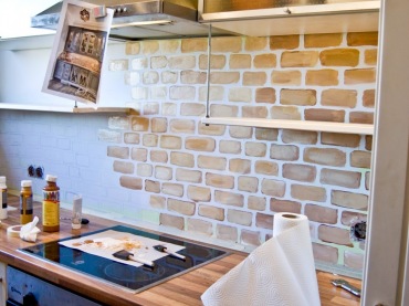 W remontowanej kuchni fragmenty ścian nad blatem wymalowano, by uzyskać efekt położonych czerwonych cegieł. Ten motyw w...