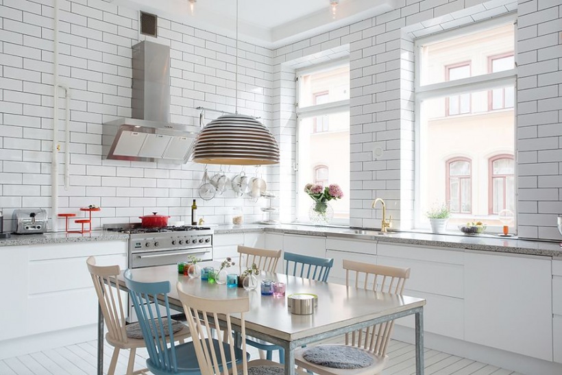 Beżowe i niebieski drewniane krzesla skandynawskie przy jednym stole w białej  kuchni