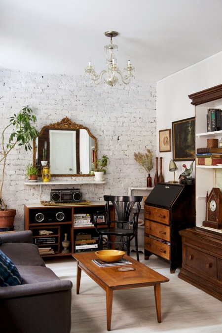 Stylowy sekretarzyk, kryształowy żyrandol w aranzacji salonu z białymi ścianami z cegły