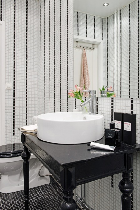 Czarna stylowa konsolka z białą okragłą umywalką,biało-czarna mozaika na ścianie w łazience
