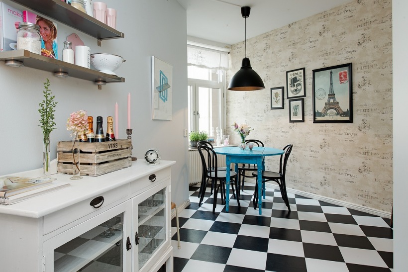 Ciekawa kuchnia w eklektycznym stylu z paryskimi plakatami,tapetą vintage na ścianie,niebieskim stołem z czarnymi krzeslami i tradycyjną białym kredensem