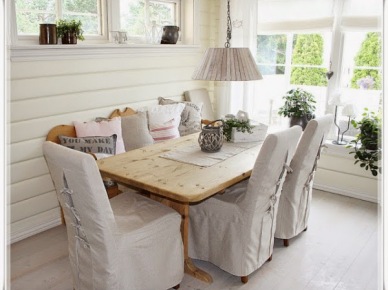 Wiejski stół z naturalnego drewna,krzesla w dekoracyjnych białych ubrankach i biała lampa na łańcuchu w aranżacji jadalni (25067)