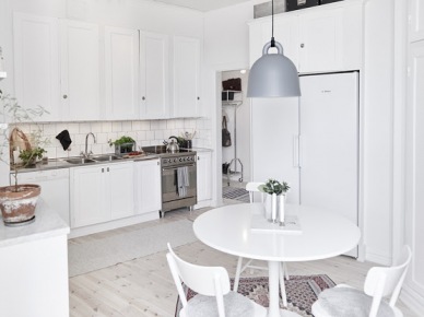 Biała kuchnia skandynawska,biały okragły stół,szara lampa wisząca nad stołem w kuchni (48135)