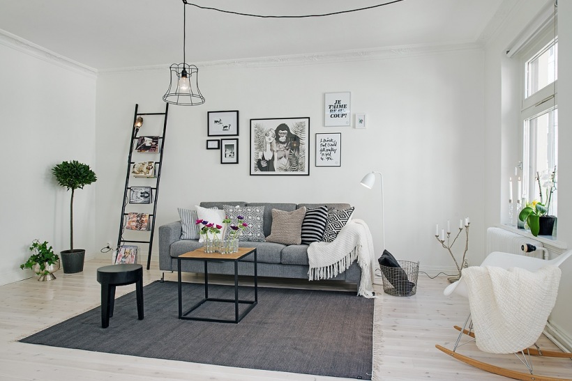 Druciana lampa,druciany kosz,szara sofa i czarna drabina w skandynawskim salonie