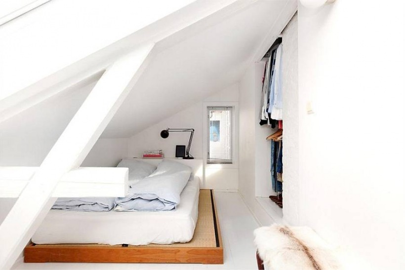 Biała sypialnia z garderobą pod skośnymi ścianami poddasza