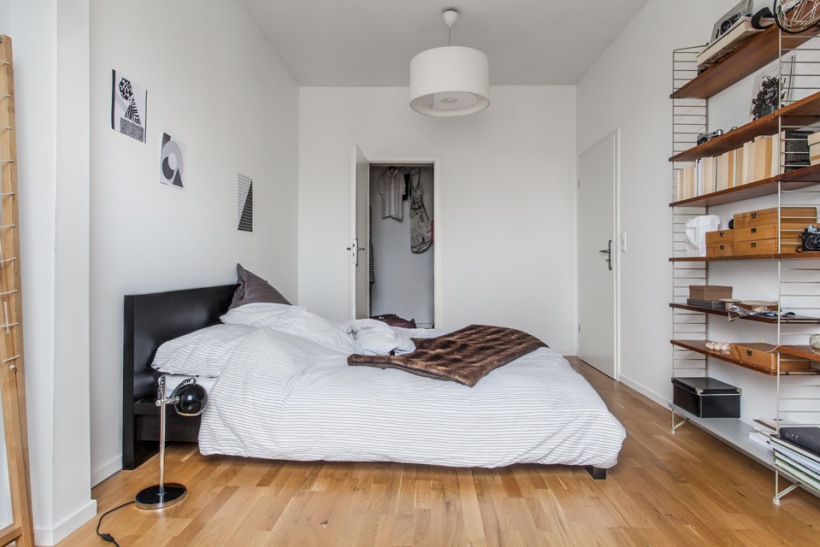 Minimalistyczna sypialnia z ażurowym regałem z drewna i metalowej konstrukcji