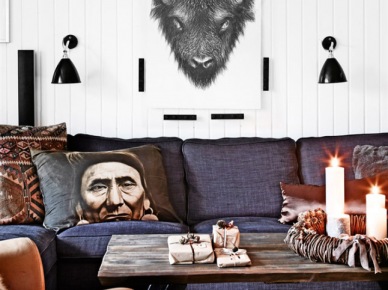 Skandynawskie grafiki,czarne kinkiety na białej ścianie nad szarą sofą z etnicznymi poduszkami (27691)