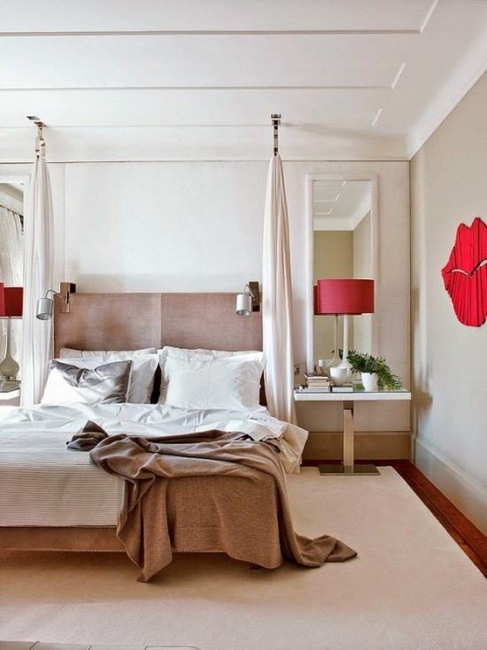 Biało-beżowa sypialnia z czerwoną lampą i plakatem