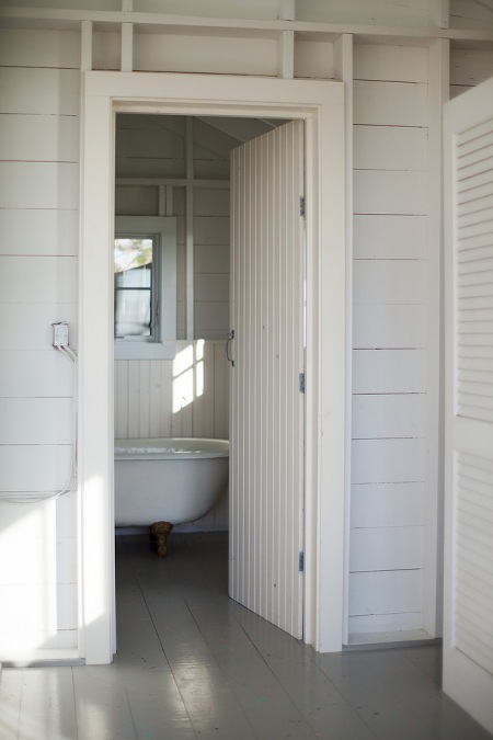 Biała łazienka  z wanną na stylowych łapkach  w małym domku letnim