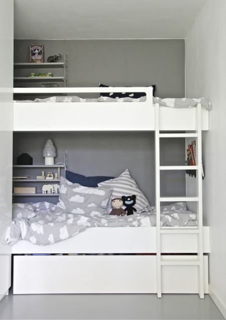 Piętrowe biale łóżka w pokoju dziecięcym z szarymi ścianami i biało-szarą pościelą