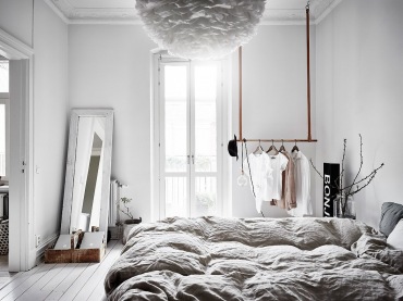 Sypialnia jest bardzo wysoka i jasna. Pod jedną ze ścian ustawiono prostokątne lustro w białej ramie jako idealnie...