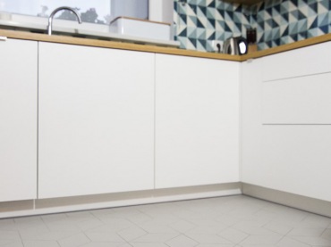 Białe szafki o gładkich frontach bez uchwytów wprowadzają nieco nowoczesnego charakteru do skandynawskiej kuchni. Kompozycja bieli i drewna rozjaśnia przestrzeń i wnosi do niej nieco przytulności. Intensywny geometryczny wzór na ścianie nad blatem w zdecydowany sposób dekoruje...