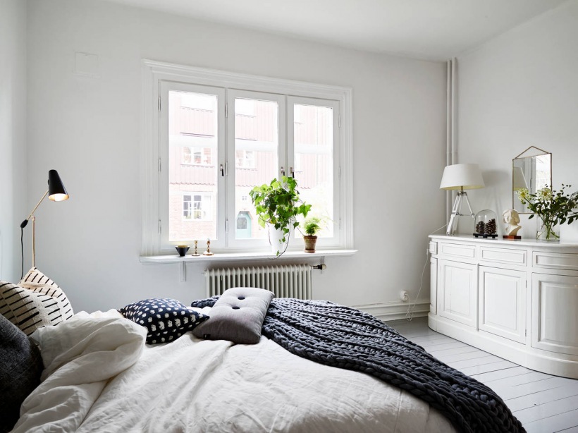 Dziergane narzuty z wełny,skandynawskie poduszki z guzikami,biała komoda i białe malowane deski w sypialni