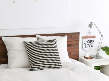 Sypialnię urządzono w bieli z dodatkiem czarnych akcentów. Na tak jasnym tle wyróżnia się także drewniana rama łóżka....