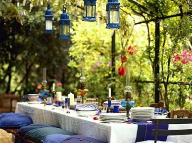 Niebieskie lataraenki, poduchy i dodatki w aranżacji biesiadnego stołu w letnim ogrodzie (25408)