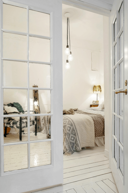Żarówki na kablu w białej sypialni w stylu skandynawskim