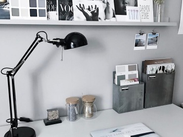 Domowe biuro urządzono w szarości, by zapewnić spójność z wystrojem części dziennej. Biały blat biurka wzmacnia koncentrację podczas pracy, a czarna lampka na nim urozmaica...