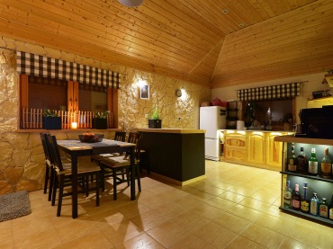 Drewniany sufit razem z kamienną ścianą podkreślają naturalny klimat domu. Jadalnia z kuchnią są dość przestronne.