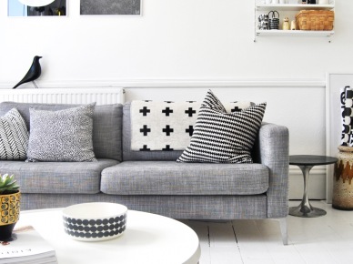 Skandynawski salon z szarą sofą,białą podłogą i grafikami na ścianie (24890)
