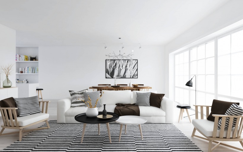 Biały skandynawski salon z drewnianymi fotelami,białą sofą,poduszkami i dywanem w czarno-białe paski