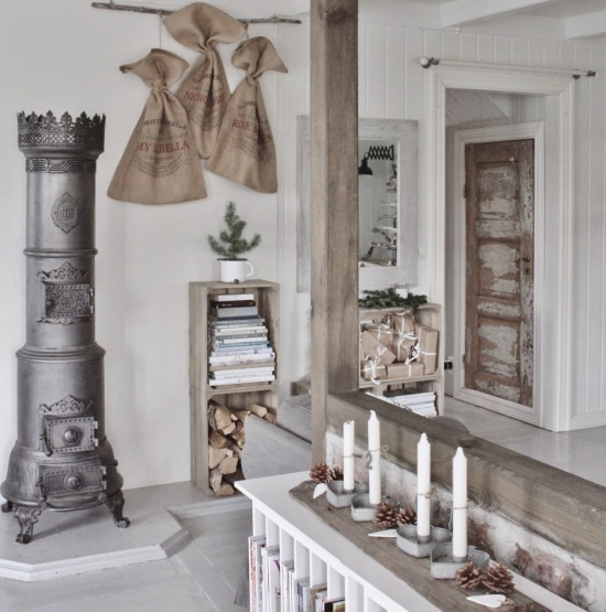 Jutowe świąteczne worki w naturalnych kolorach,retro kominek żeliwny, drzwi vinatge i dekoracja świąteczna ze świecznikami i szyszkami w metalowych pojemnikach