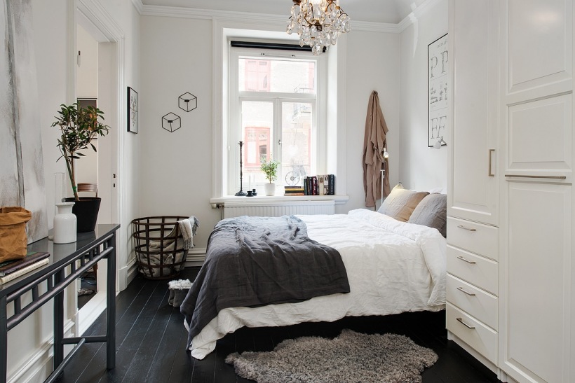 Francuski kryształowy zyrandol,czarna konsolka,metalowy ażurowy kosz i czarna podłoga z desek w aranżacji białej sypialni