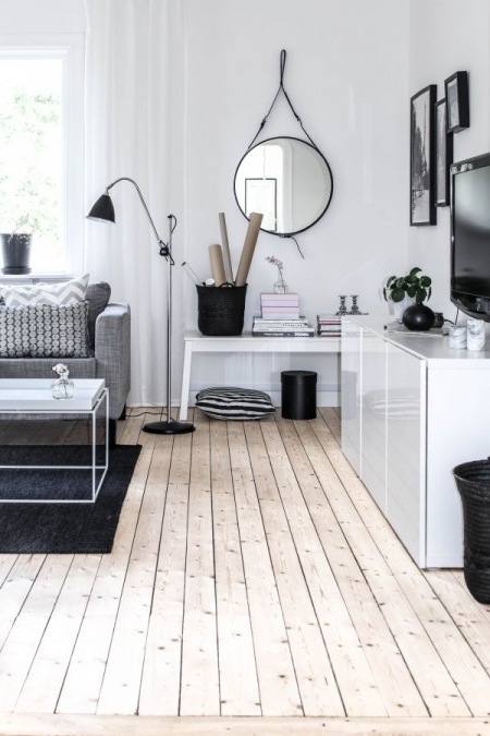 Biało-czarna aranżacja salonu skandynawskiego z podłogą z desek z naturalnego drewna