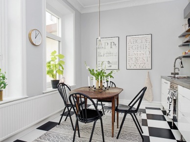 Posadzka ułożona w szachownicę,tkany dywan skandynawski z etnicznym wzorem,czarne krzesła przy drewnianym brązowym stole (28576)