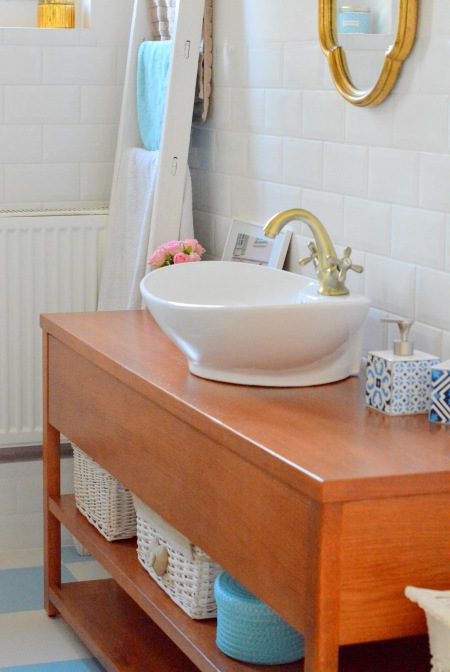 Drewniana komoda w białej łazience ze złotymi dodatkami