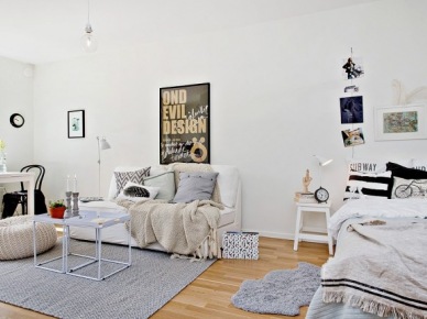 Czarno-białe poduszki na łóku stojącym w salonie z białymi stolikami,białą sofą i szarym dywanem (24697)