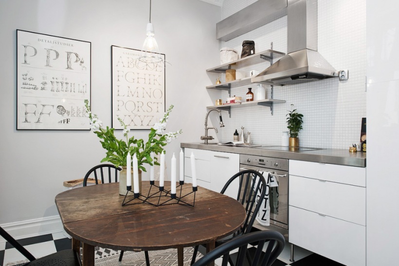 Biała kuchnia z betonowym blatem,czarne krzesła skandynawskie,owalny stół,typografie na ścianie w kuchni