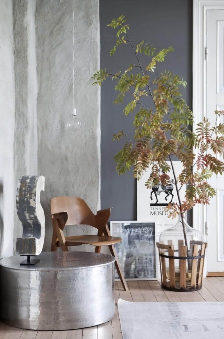 Srebrny metalowy stolik siedzisko,wapienne tynki i czarna farba na ścianie, , żarówka na białym kablu,drewniane krzesło w nowoczesnym stylu
