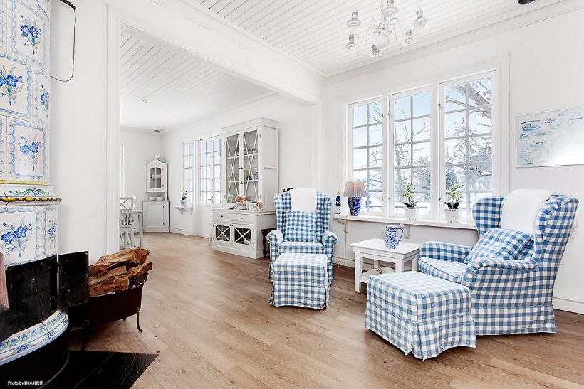 Otwarta przestrzeń jadalni z pokojem wypoczynkowym ze stylowym biało-niebieskim  kominkiem