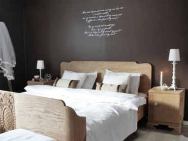 typowa drewniana sypialnia, jak sprzed lat, od wiejskiego, zdolnego stolarza - a sypialnia robi wrażenie ! na tle zupełnie czarnych ścian, z białą inskrypcją, i białymi lampkami na stolikach nocnych - jest świeża, przyjazna i oryginalna! to przykład, jak używać czerni na ścianach , by w zestawie nie była mroczna i ponura - w końcu to sypialnia ! tutaj można mieć tylko miłe...