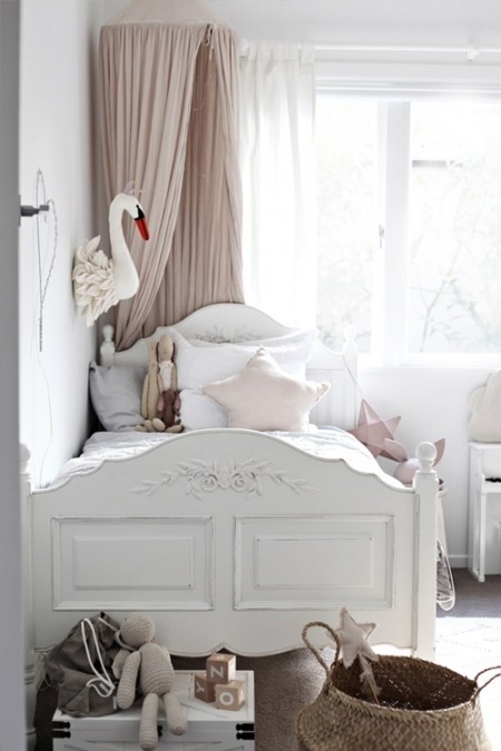 Białe rzeźbione łóżko w pastelowym pokoju dziecięcym