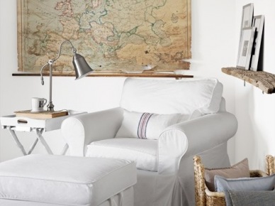 Dekoracyjna mapa Europy, biały fotel  i drewniana półka w aranżacji salonu (28680)