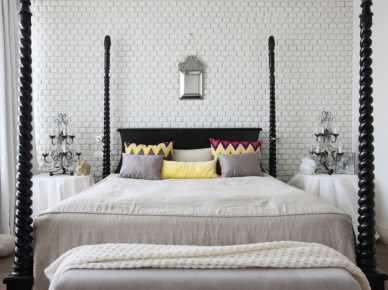 Biała cegła na ścianie w sypialni ze stylowym drewnianym łóżkiem,kolorowymi poduszkami w zygzaki i stylowymi świecznikami lampami na stolikach (27060)