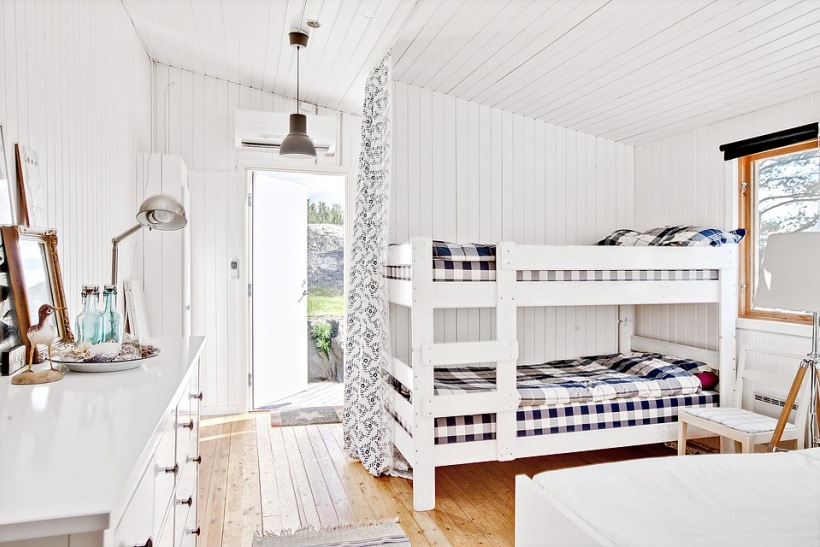 Piętrowe białe łóżka z granatowo-biała dekoracja w aranżacji pokoju dla dzieci