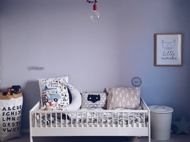 Wysoki pokoik dziecięcy wypełniają proste meble i wzorzyste dodatki. Obok łóżka postawiono dekoracyjne kosze, które pomagają przechowywać zabawki i drobiazgi...
